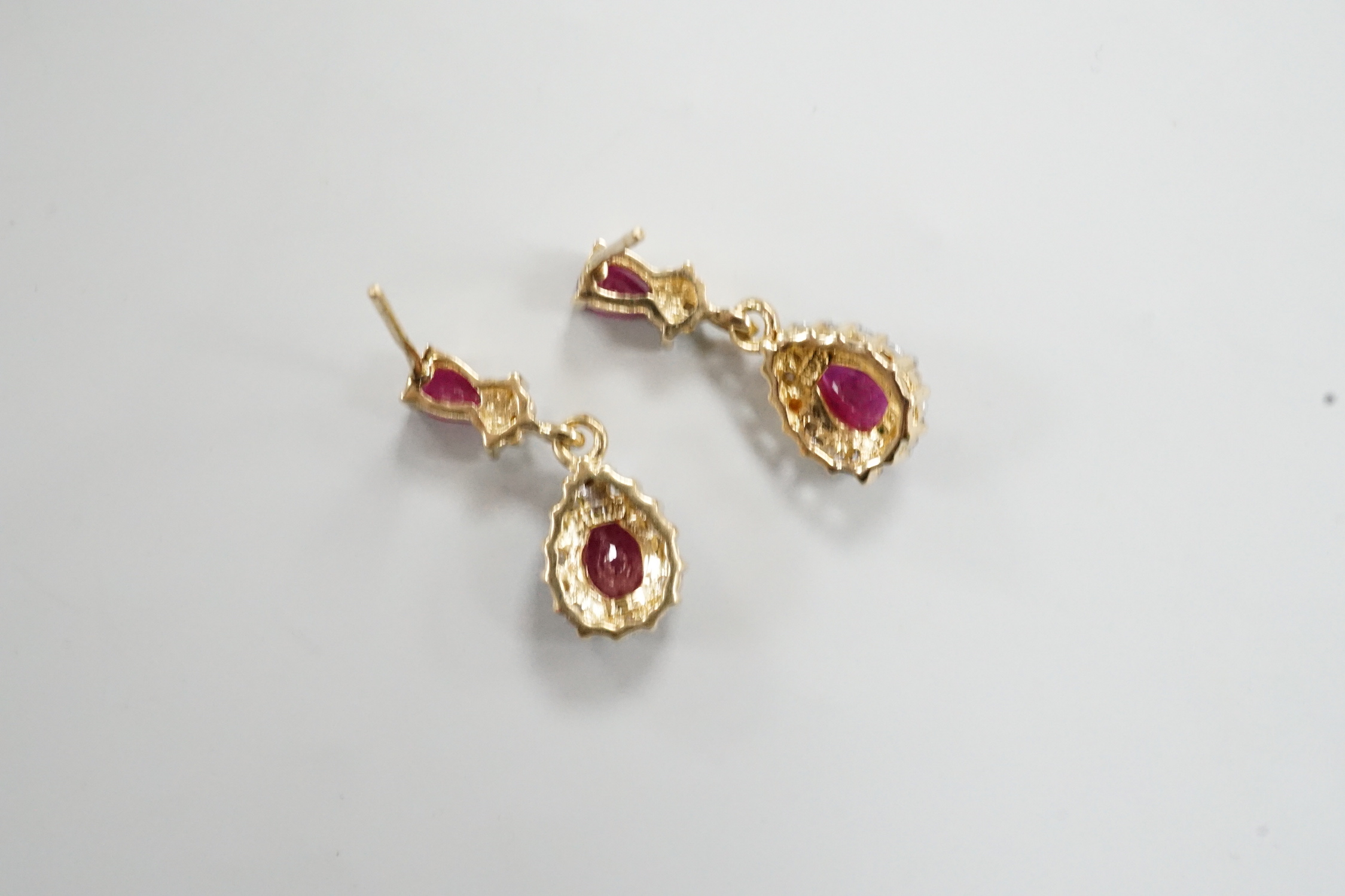 A modern pair of 18k yellow metal, ruby and diamond set pear shaped cluster drop earrings, 20mm, gross weight 3 grams.